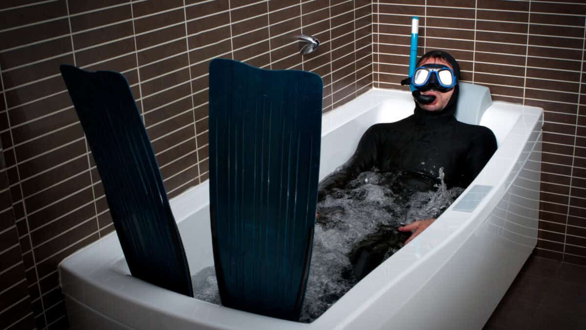 Man with diving gear on in a bathtub.