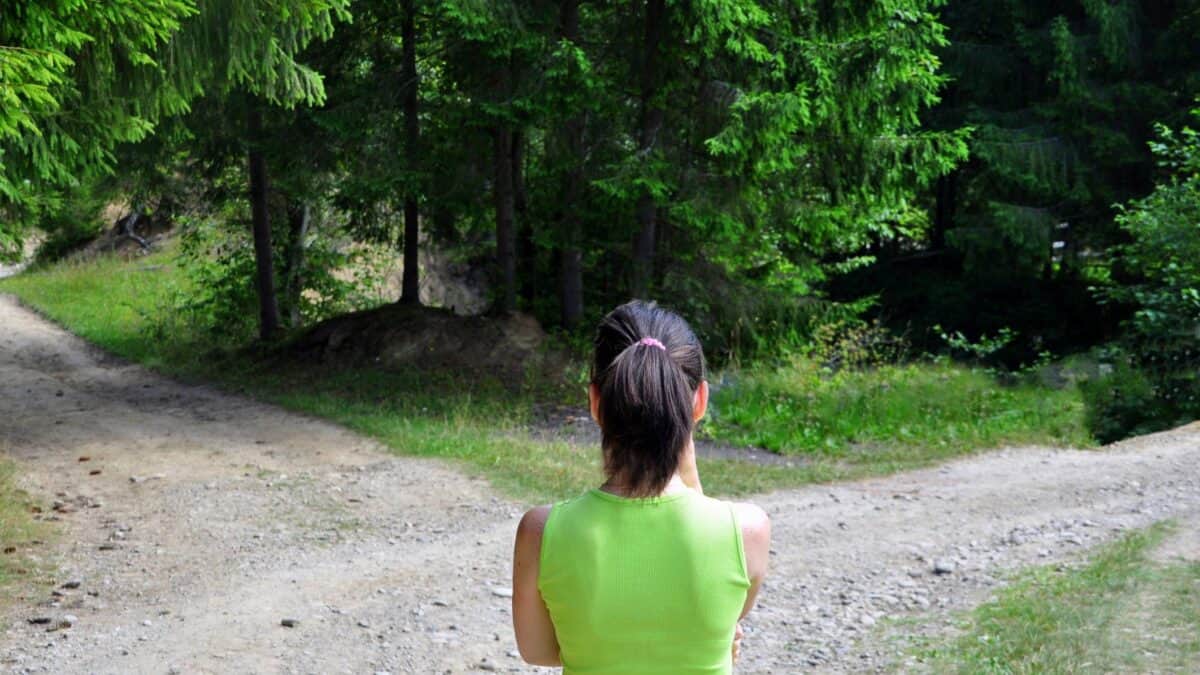 A young woman with a ponytail stands at the crossroads, trying to choose between one way or the other.