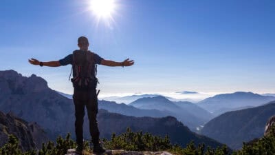 Man with backpack spreading his arms out and soaking in the sun.