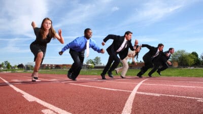 Group of people dressed in business attire racing on track.