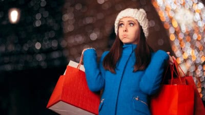 Stressed shopper holding shopping bags.