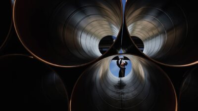 View of a mining or construction worker through giant metal pipes.