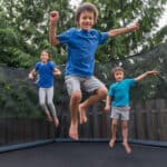 Siblings jumping on a trampoline.