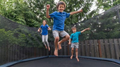 Siblings jumping on a trampoline.