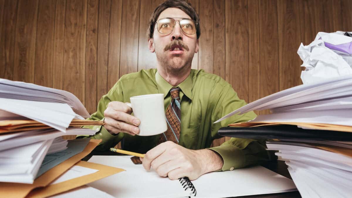 Stressed man looking ahead with a lot of paperwork on both sides.