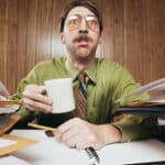 Stressed man looking ahead with a lot of paperwork on both sides.