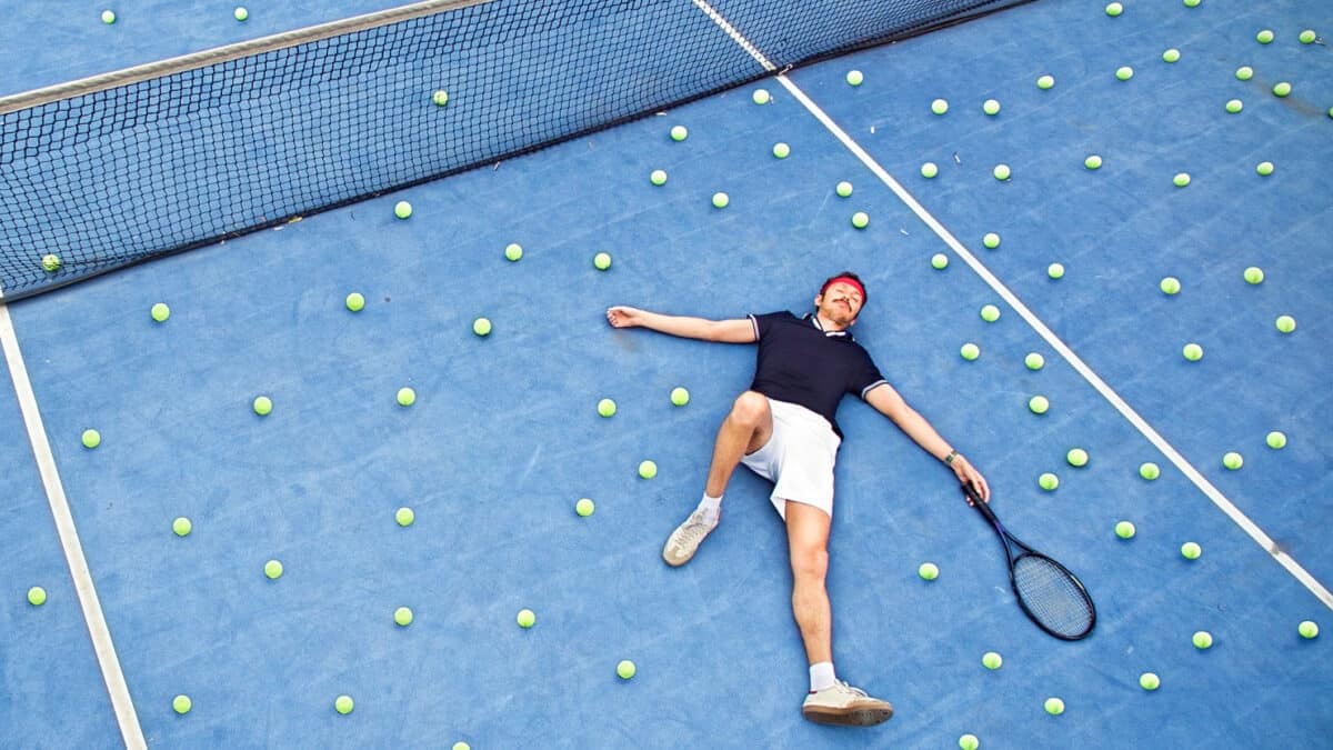 A man lays on a tennis court exhausted.