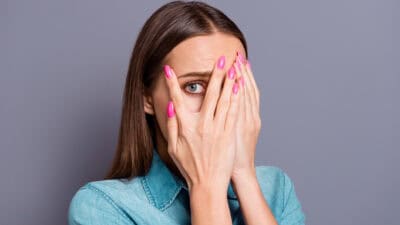 Woman with a scared look has hands on her face.