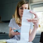 Woman looking at paper bill and counting expenses.