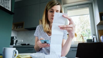 Woman looking at paper bill and counting expenses.