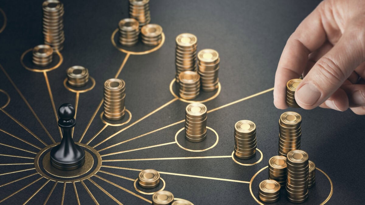 Man putting golden coins on a board representing multiple streams of income.