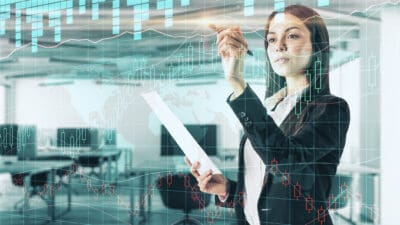 Woman using a pen on a digital stock market chart in an office.