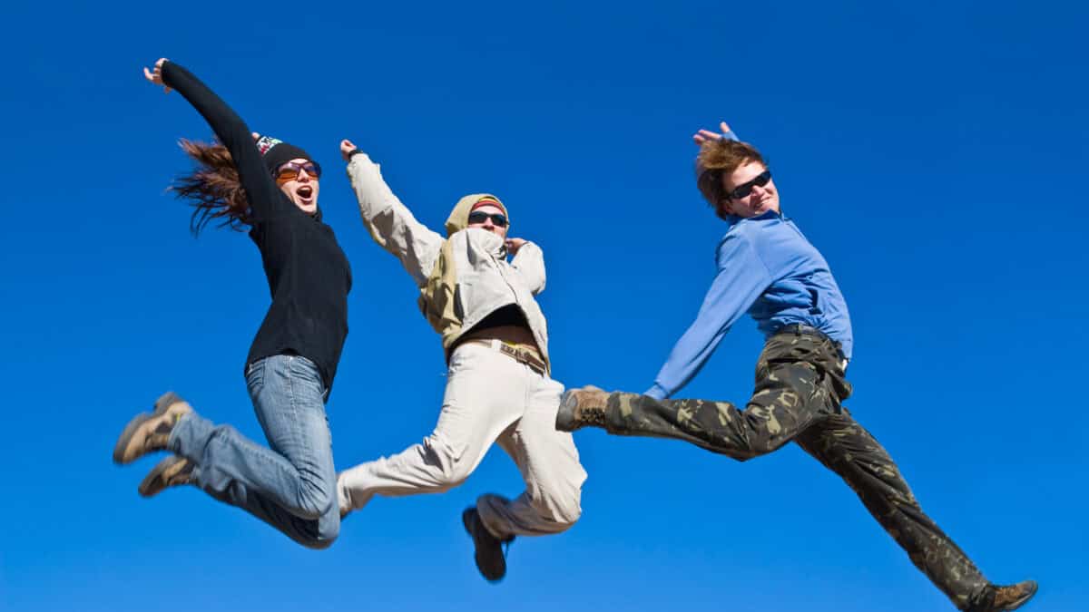 Three people jumping cheerfully in clear sunny weather.