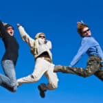 Three people jumping cheerfully in clear sunny weather.